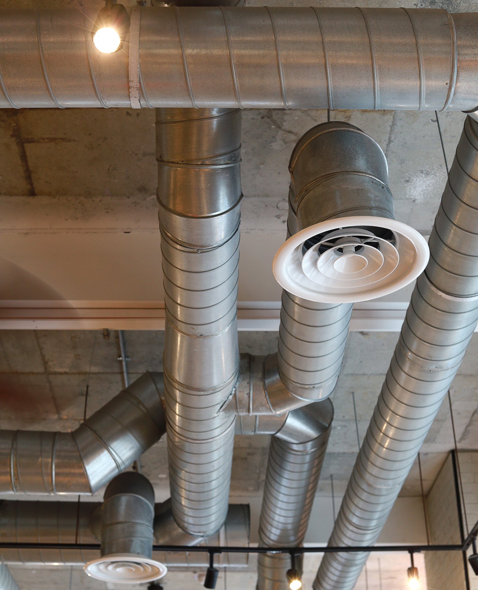 An exposed metal HVAC duct system with air vents in a commercial or industrial building, providing ventilation and airflow.