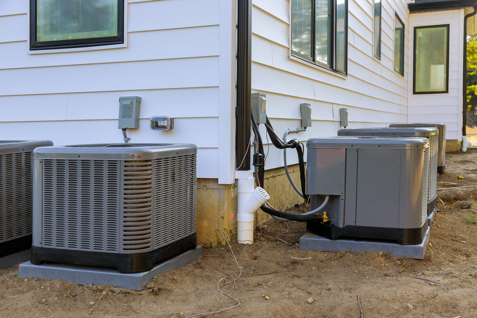 Several outdoor HVAC units installed along the exterior of a residential building, providing heating and cooling.